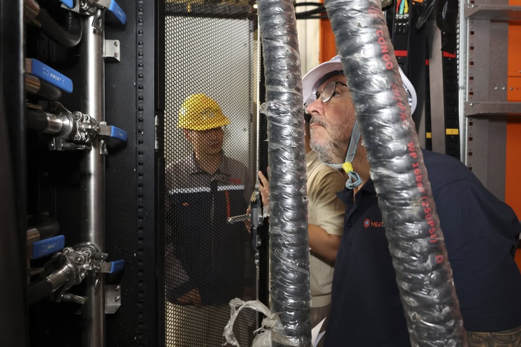 HeatLoad Managing Director Dave Wolfenden inspecting liquid cooling manifold hoses during data centre testing.